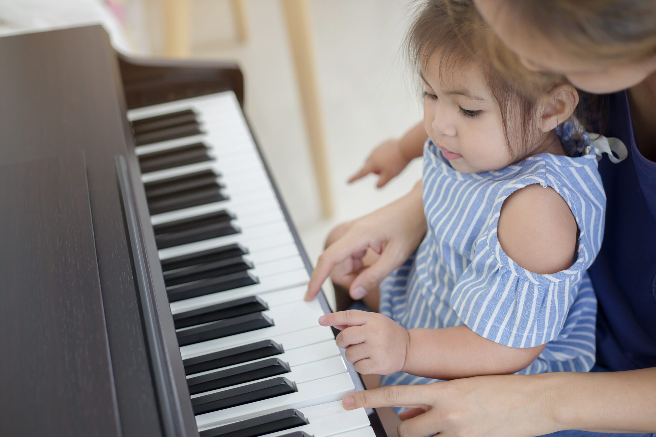 toddler learning piano with parent